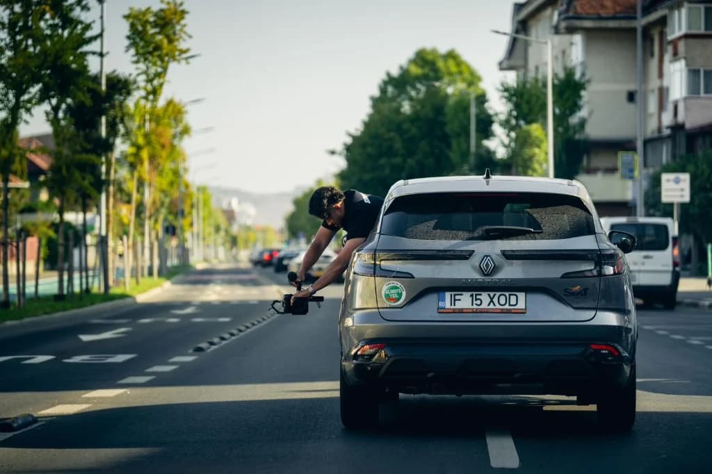 Adryan leaning from a moving car to film a low tracking shot with a camera gimbal