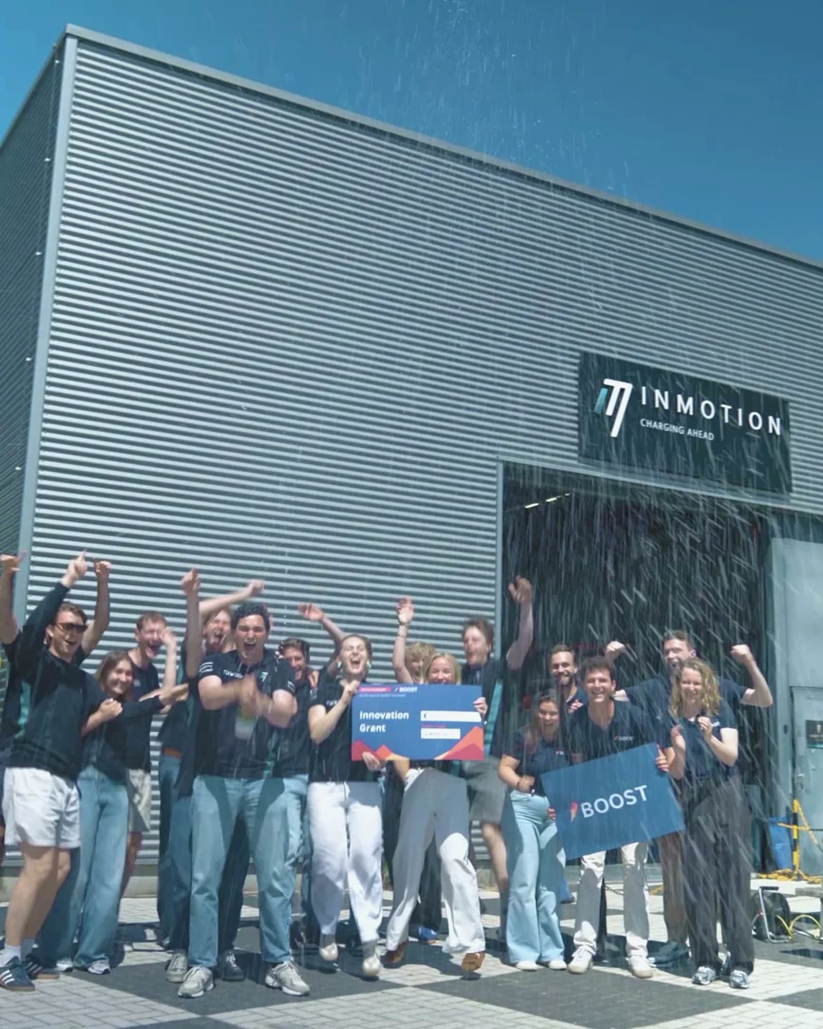 Student teams cheering with champagne as Boost Innovation Grant signs are held high