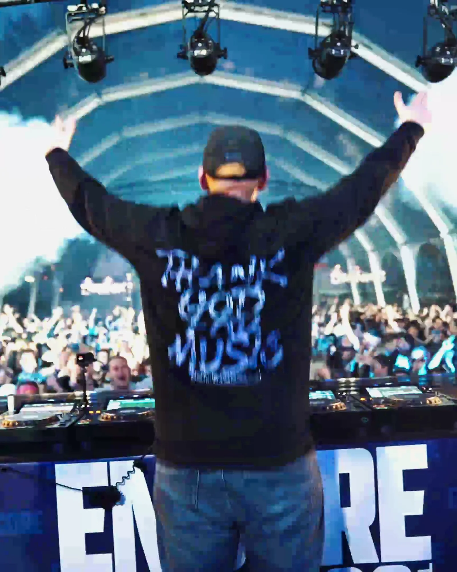 DJ facing the crowd from the ENCORE booth with arms raised