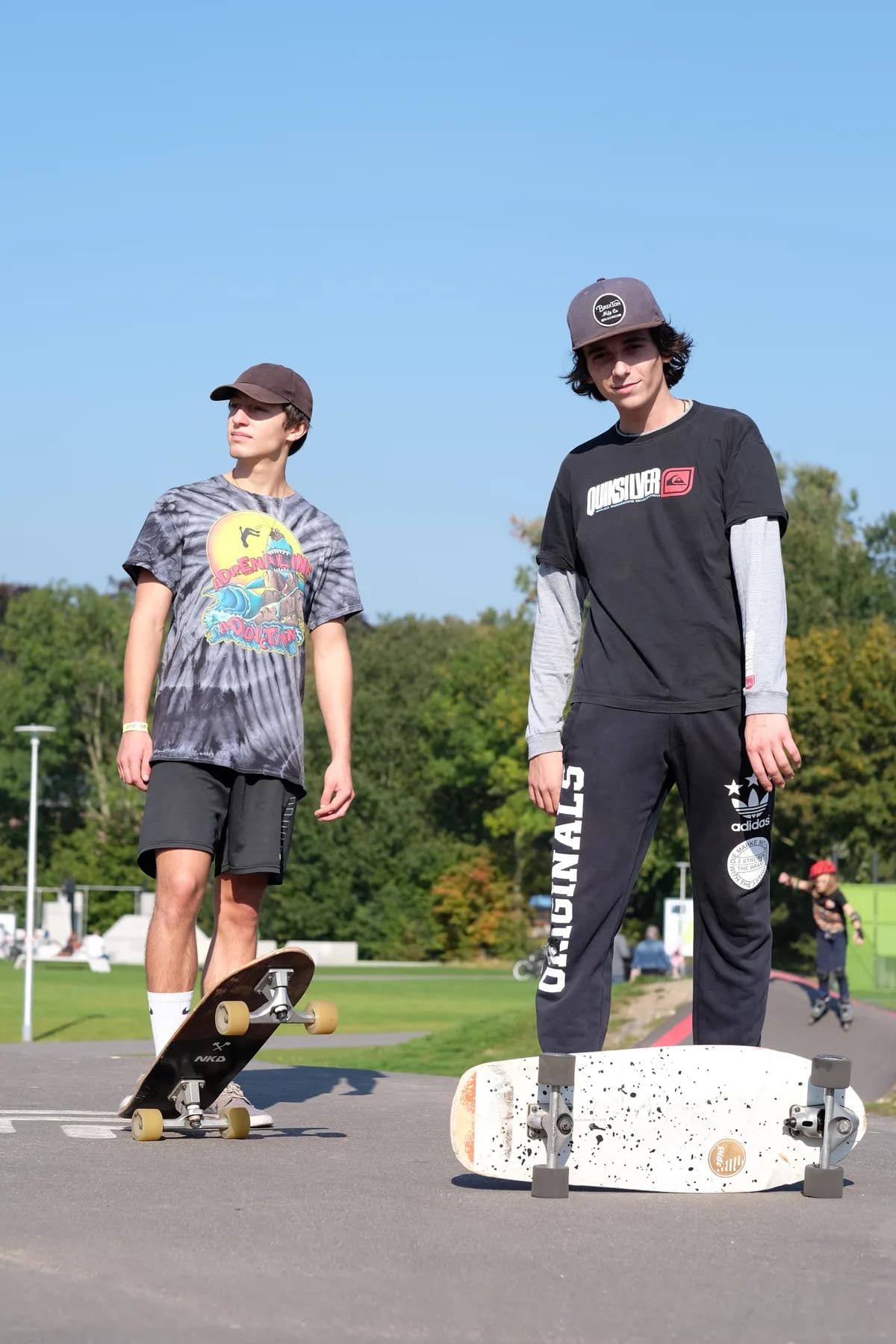 Two skaters in streetwear posing outdoors with boards