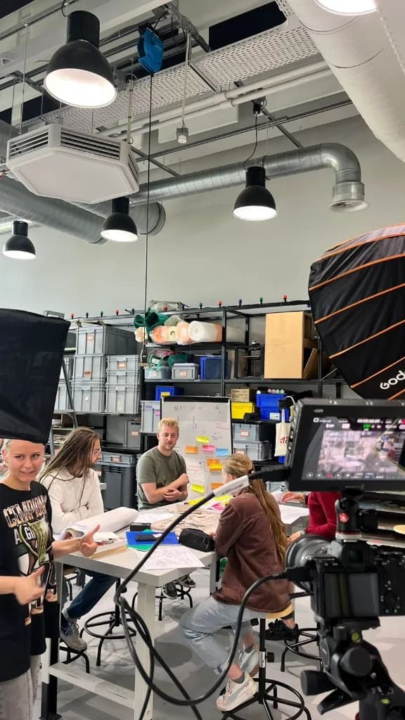 Creative team gathered around a planning table with cameras and studio lights in an industrial space