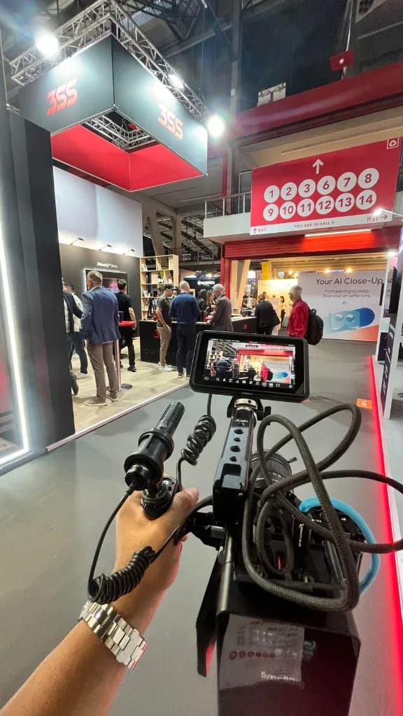 First-person view of a camera rig filming a busy trade show hall