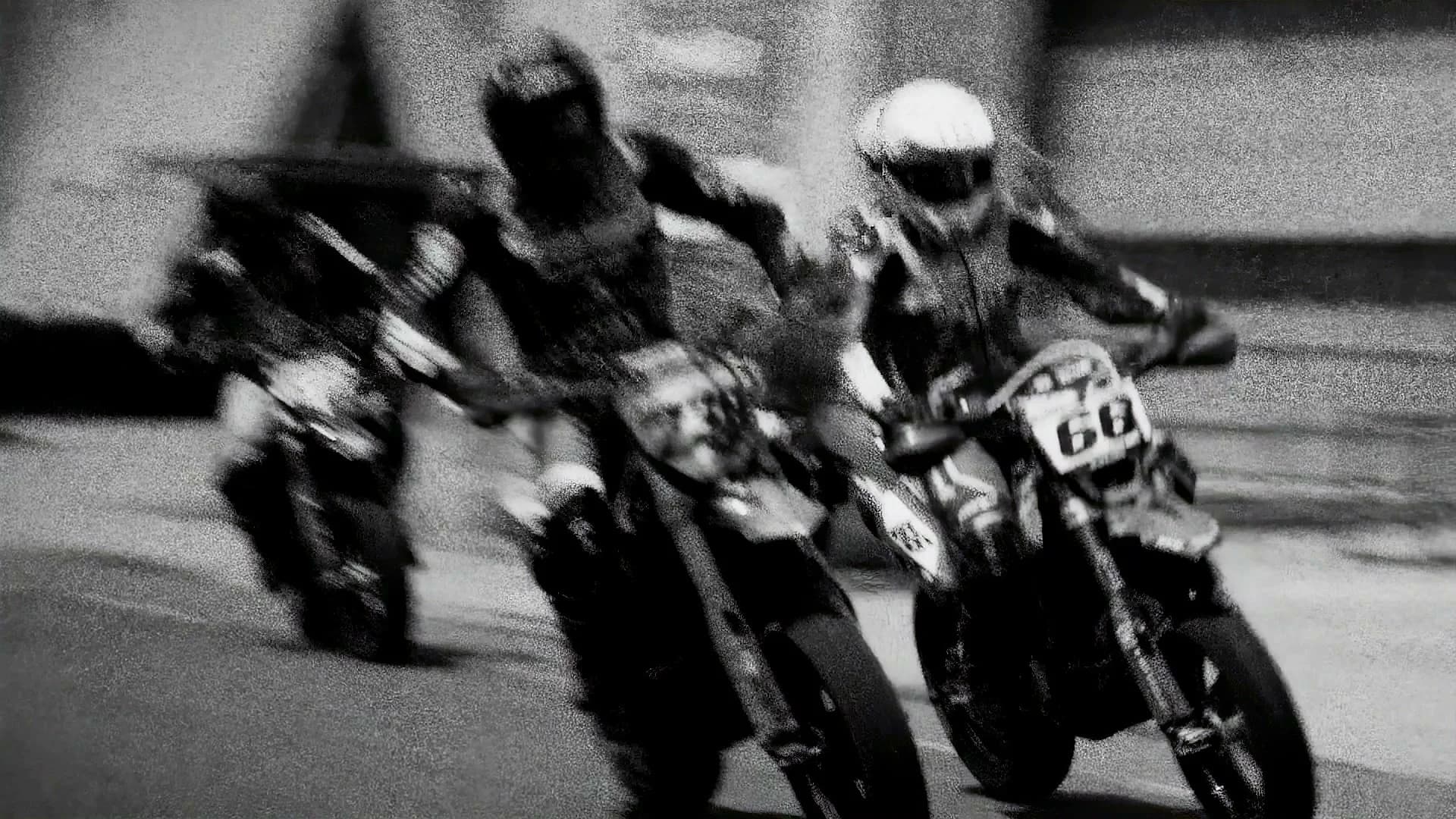 Black-and-white still of two riders in motion blur
