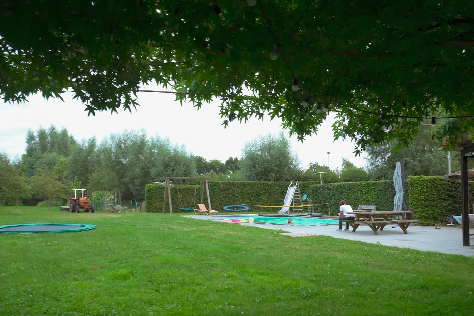 Garden, pool and swing set under the trees at Woonboerderij Schijndel